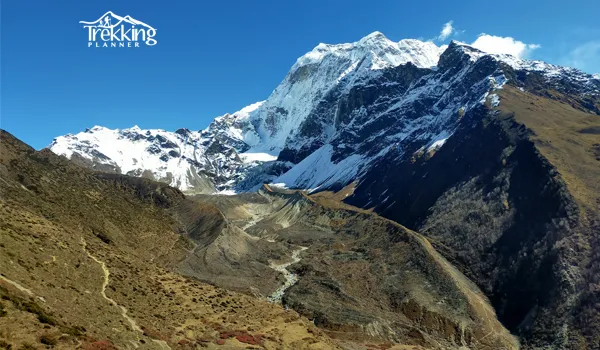 Trekkers walking on Manaslu Circuit trail during autumn with crisp weather and snow-capped Himalayan peaks
