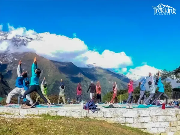group doing yoga pose outdoors with clear view of Himalayan mountains in Nepal