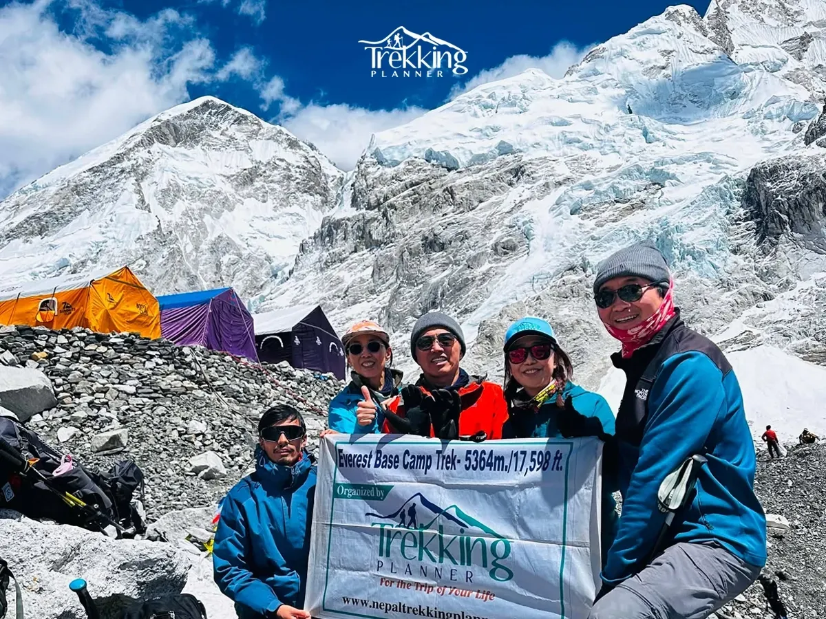 Trekkers celebrating at Everest Base Camp during the Everest Base Camp Trek with Khumbu Glacier in the background