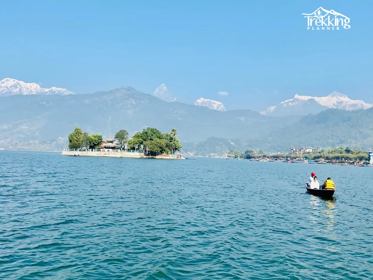 Traditional boats on Phewa Lake with reflections of Pokhara city and surrounding hills during a city sightseeing tour.