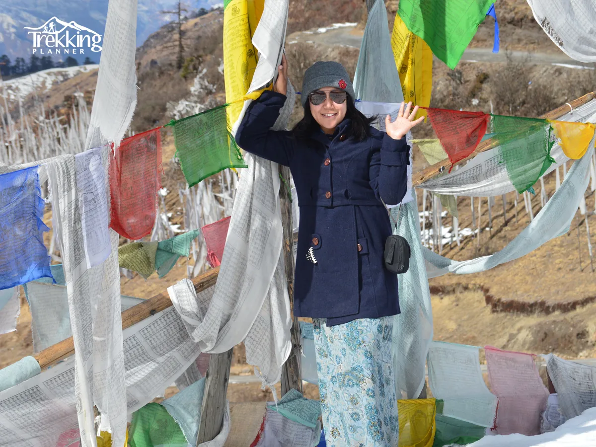 Traveler surrounded by colorful Buddhist prayer flags during the Bhutan Dragon Tour.