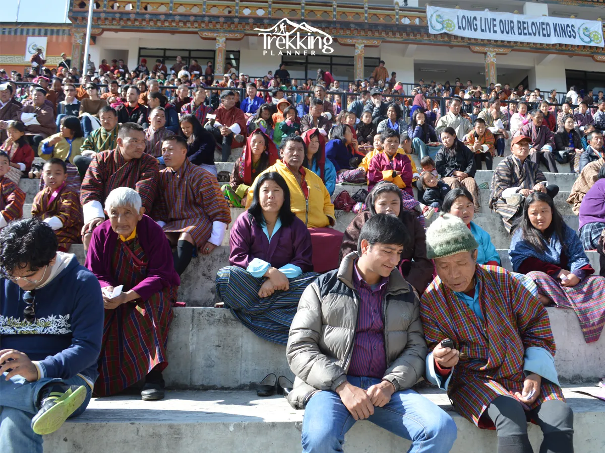 Local people in traditional Bhutanese attire watching the Tshechu Festival celebration.