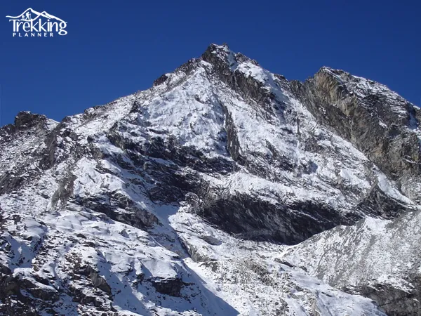 Climber ascending the snowy ridge of Pokalde Peak with panoramic Himalayan views in Nepal