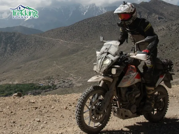 Upper Mustang bike tour riders on motorbikes approaching Lo Manthang desert landscape in Nepal Himalayas