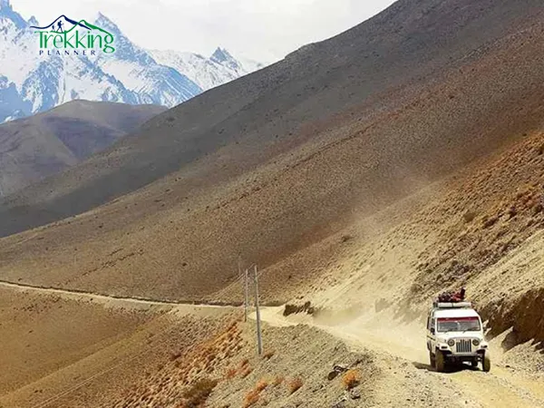 Jeep driving through the desert landscape of Upper Mustang with Himalayan mountains in the background during Upper Mustang Jeep Tour